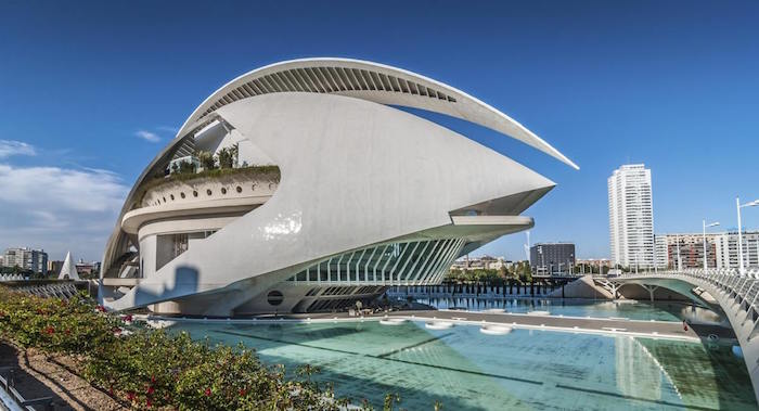 post modernity, smooth and glossy white building, with an unusual shape and rounded edges, built over an blue artificial pool of water