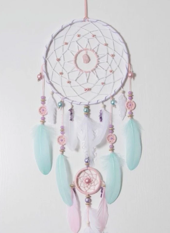 baby pink and white, and pastel turquoise feathers, small ornaments and beads, decorating a white dreamcatcher, how to make a dreamcatcher 