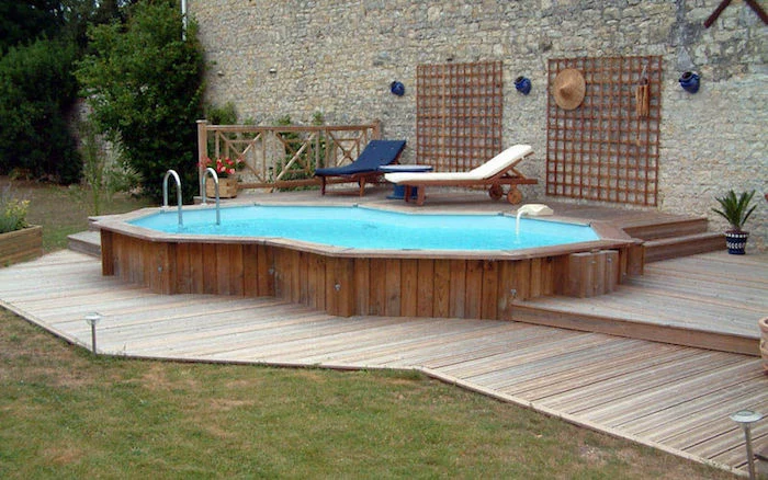 teal colored pool, lined with wooden planks, in a garden with a stone wall, decorated with wooden details