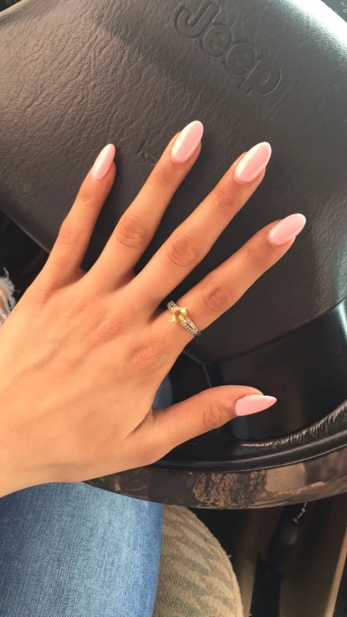 jeep steering wheel, under a slim hand, with long fingers, and oval shaped nails, painted in pale pink nail polish