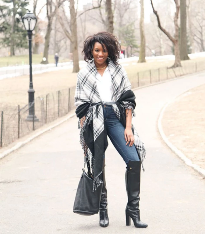 over the knee, black leather boots, over skinny jeans, combined with a whote blouse, and a two-tone grey oversized scarf, worn like a cardigan, scarf outfits, on a smiling black woman