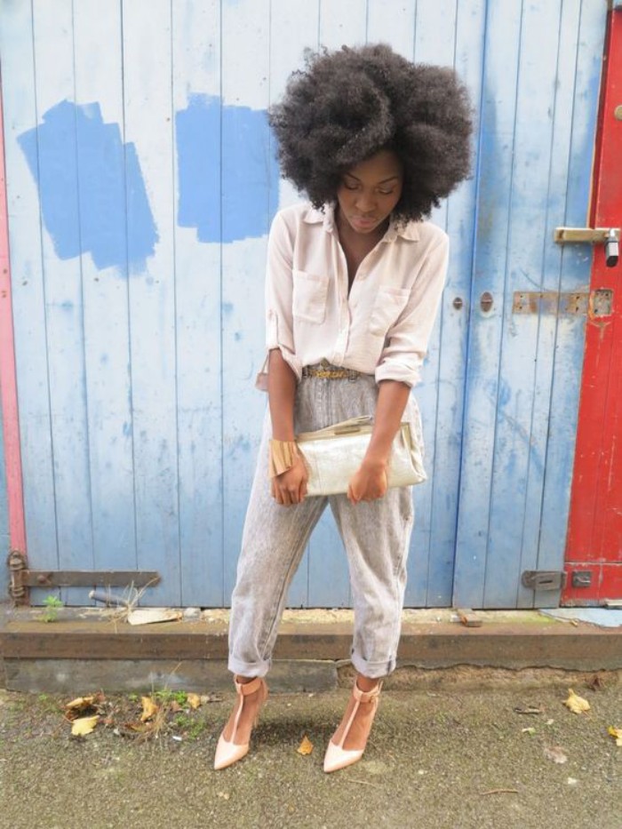 acid wash jeans with rolled bottoms, and a pale cream shirt, worn by a black woman, with a voluminous afro, in high heels and holding a large clutch bag, 80s fashion trends 