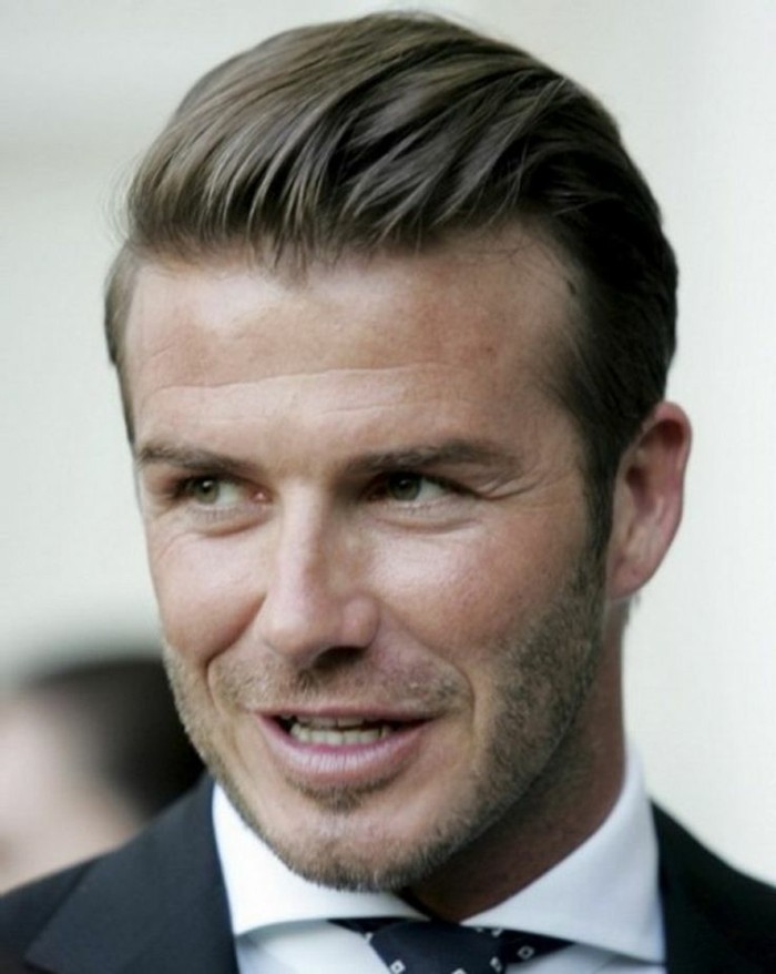 david beckham with slicked back hair, and short stubble, modern haircuts for men, smiling while looking to one side