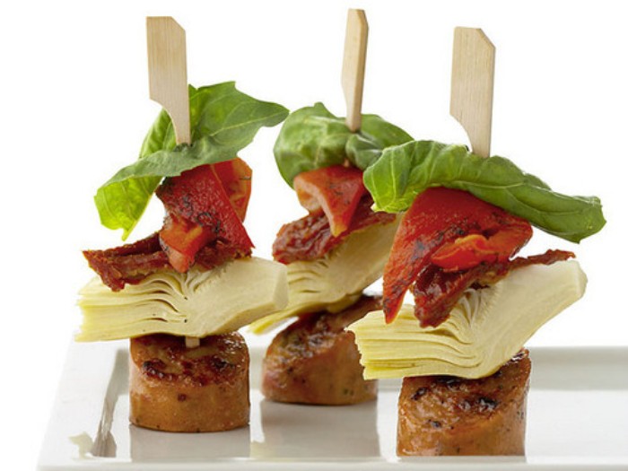 red peppers and artichoke hearts, skewered with salami and basil leaves, then grilled and served on a white plate