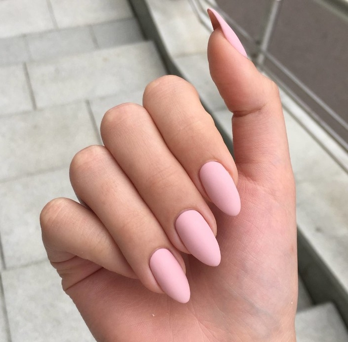 hand with folded fingers, seen in close up, with pastel pink, matte nude nails, pointy oval shape