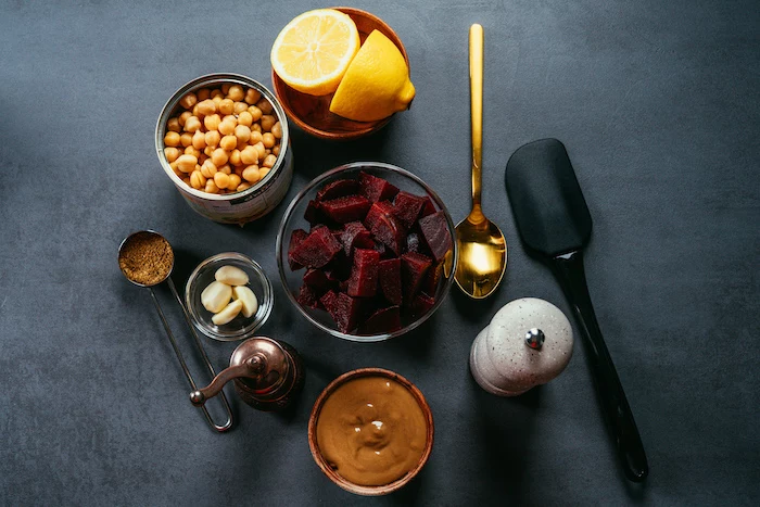 necessary ingredients, beet hummus recipe, arranged in different bowls, placed on black surface