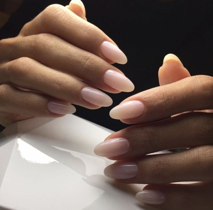 slender fingers on two hands, with oval manicure, painted in nude pink nail polish, in a milky hue 