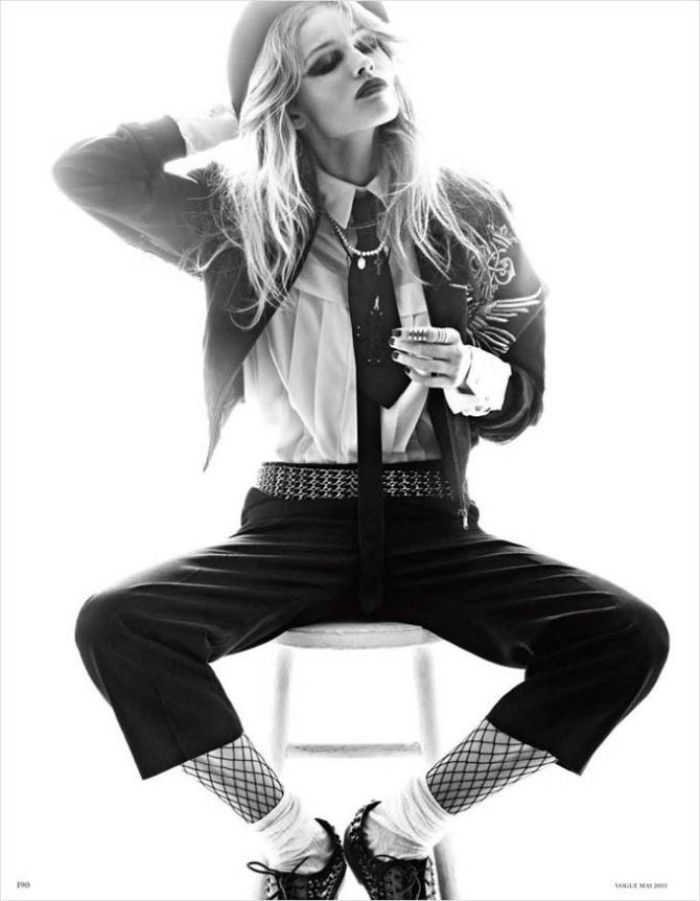 greyscale image of a young woman, sitting on a stool, dressed in an outfit, inspired by michael jackson in the 80s, cropped dark trousers, white shirt and tie, jacket with applique details