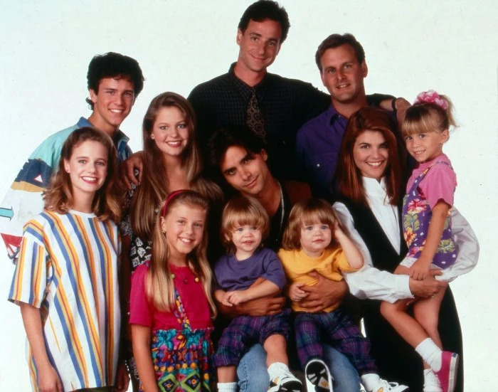 entire cast of the sitcom full house, dressed in vintage outfits, oversized colorful clothes, vests and bold patterns, 80s costumes men and women, bob saget and the olsen twins