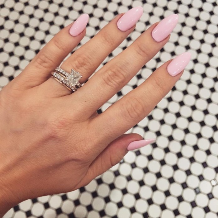 creamy pale pink nail polish, on a hand with long fingers, wearing a silver ring, with a large diamond, stiletto nails