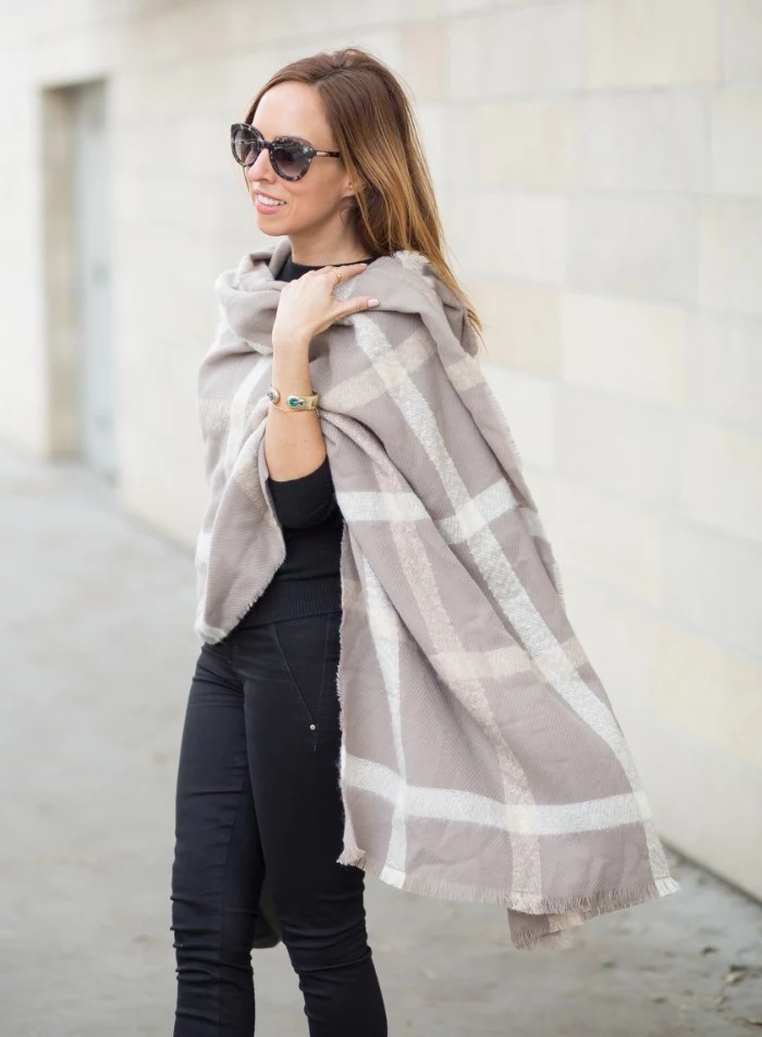 oversized pale grey shawl, with off-white striped pattern, worn by a woman dressed in black, how to tie a blanket scarf 