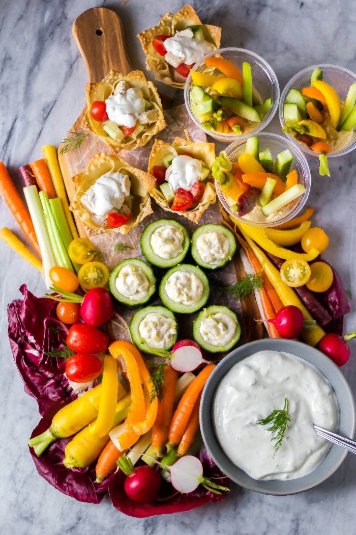 hors d oeuvres recipes, a rich selection of vegetable appetizers, cucumber slices with yoghurt sauce, chopped carrots and celery, cherry tomatoes and radishes