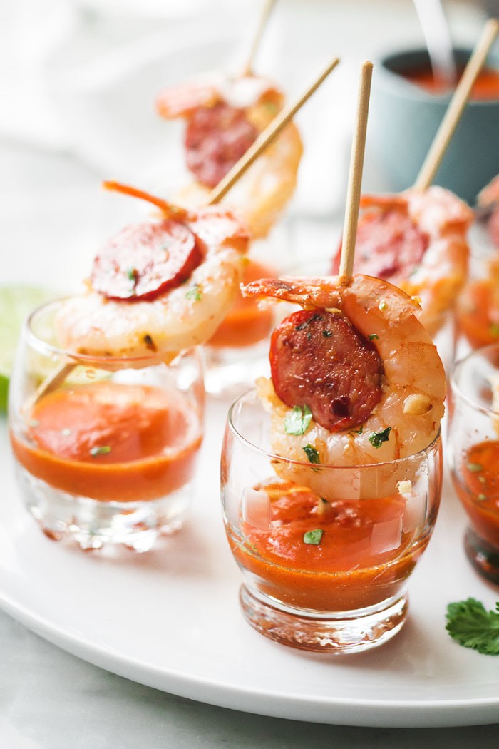 prawns and chorizo slices, skewered with a wooden stake, and placed over shot glasses, half filled with an orange sauce, horderves