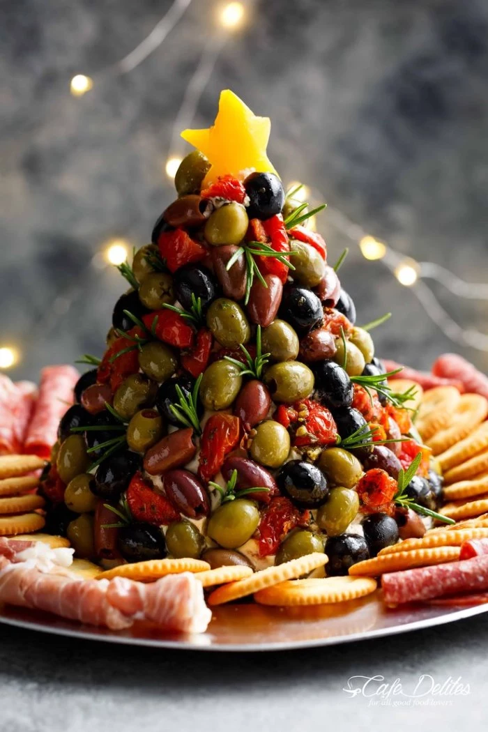 olives stacked in the shape of a christmas tree, and topped with a yellow star, hor d oeuvres ideas, on a plate with crackers and salami