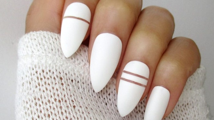 bright white nail polish, decorated with clear thin lines, on almond shaped nails, attached to a hand, gripping a white knitted sleeve
