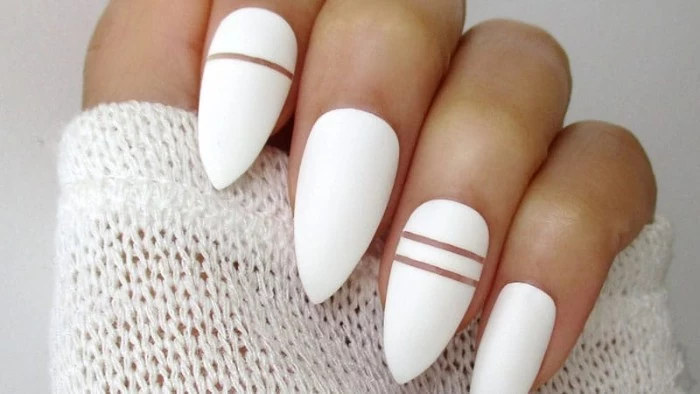 bright white nail polish, decorated with clear thin lines, on almond shaped nails, attached to a hand, gripping a white knitted sleeve