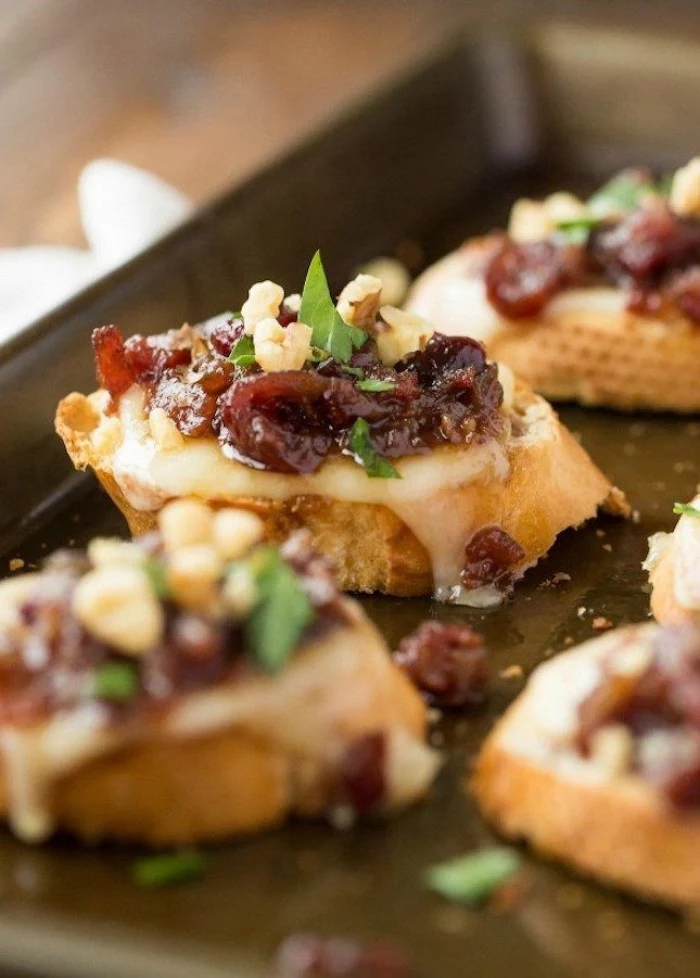 metal baking tray, containing several pieces, of grilled cheese bruschetta, topped with cranberry confit, and fresh basil