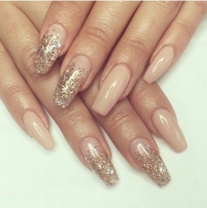 ballerina shaped manicure, long with square tips, covered in gold glitter, pink nude nails, on two hands