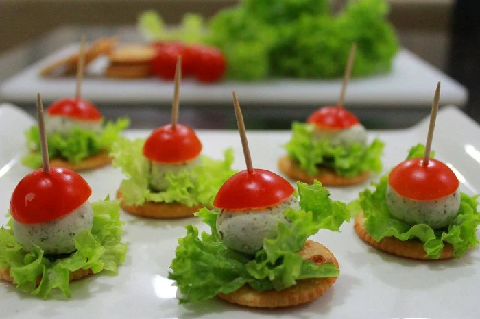 appetizers for a crowd, feta cheese balls, with small lettuce leaves, and cherry tomoato halves, skewered with toothpicks