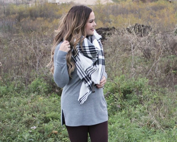 tunic sweater in pale grey, worn over black leggings, by a woman with light brunette hair, in loose curls, white and grey oversized scarf