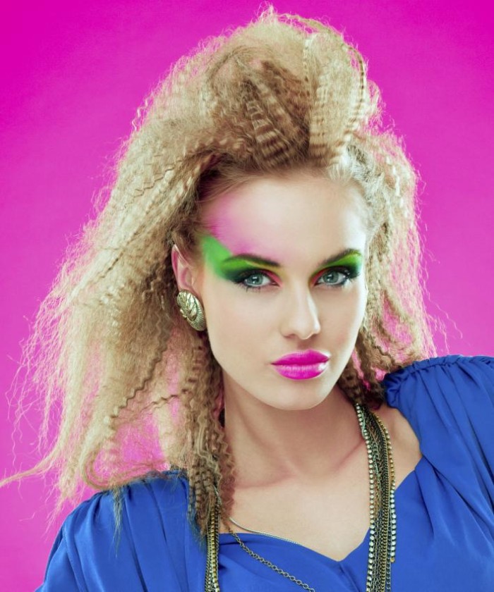 teased blonde hair, messy and voluminous, worn by a young woman, with neon colored make up, 80s costumes, electric blue top with shoulder pands