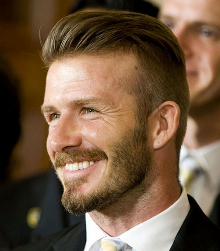 footballer david beckham, with brunette hair, styled in his trademark, slicked back quiff, short sides long top haircut, beard and mustache