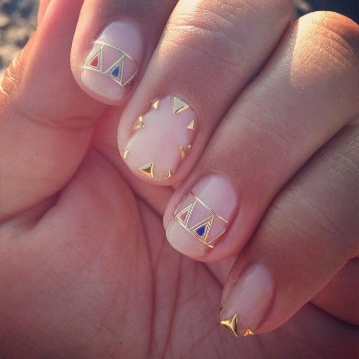 red and blue and gold nail decal stickers, on a short manicure, with pink nude nails, seen in close up