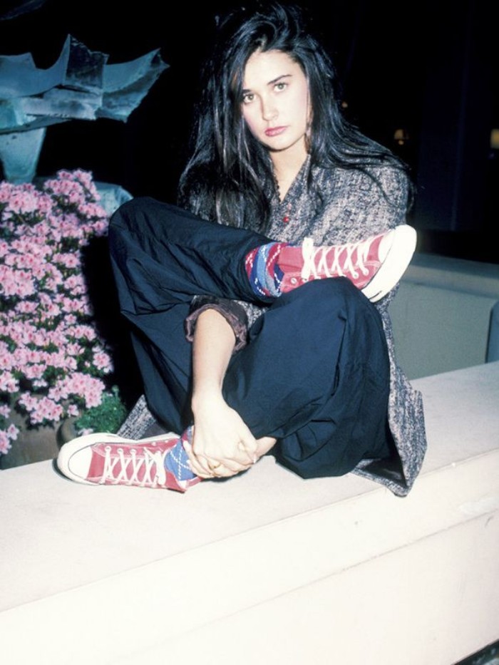 long black hair, worn by demi moore, dressed in black baggy trousers, and a patterned top, 80's fashion pictures, with colorful socks, and red converse sneakers