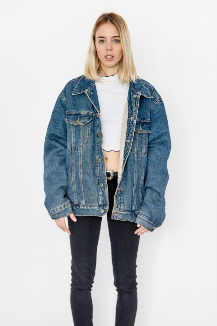 oversized denim jacket, worn over a white crop top, and dark skinny jeans, 80s fashion trends, on a young blonde woman