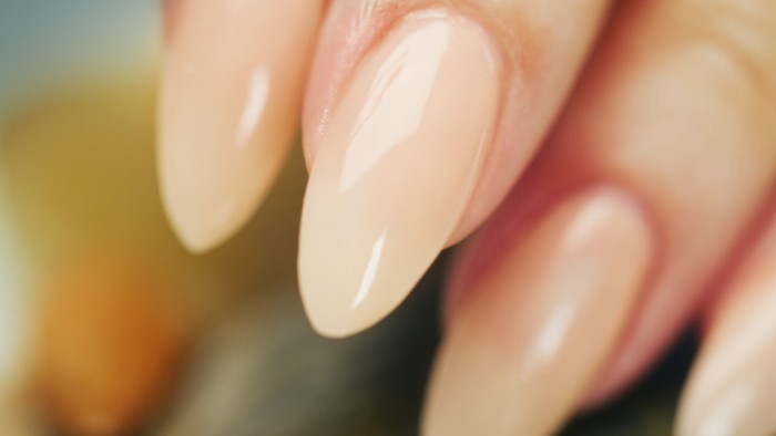 semi-tanslucent nude beige nail polish, on several glossy stiletto nails, seen in extreme close up