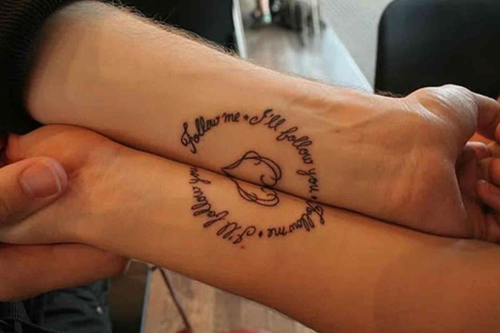 two tattoos forming one mage when presed together, featuring a heart, and the words follow me, i'll follow you, husband and wife tattoos, black ink on two wrists