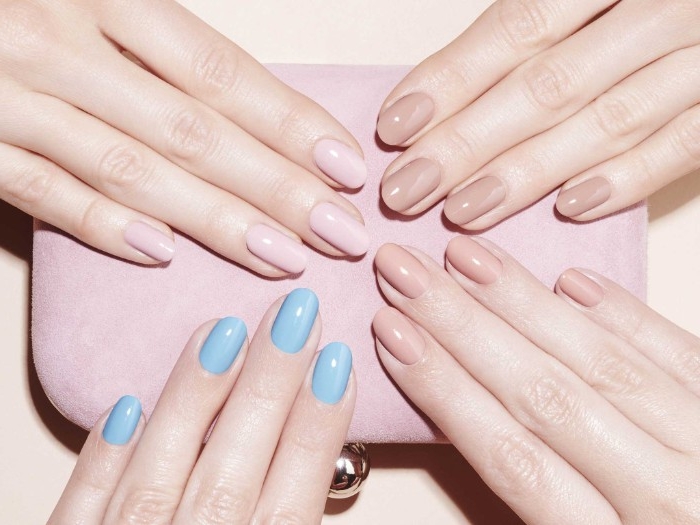 three hands with different, nude gel nails, pink and beige hues, and one hand with teal blue manicure