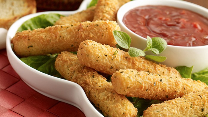 hors dourves, breaded and fried, mozzarella cheese sticks, in a white plate with lettuce and basil, and a red salsa-like dip