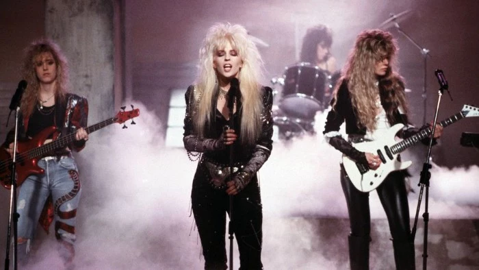 punk glam rock band, performing on a stage, 80s fashion trends, teased vouminous and messy hair, leather trousers and jackets, jeans with applique details