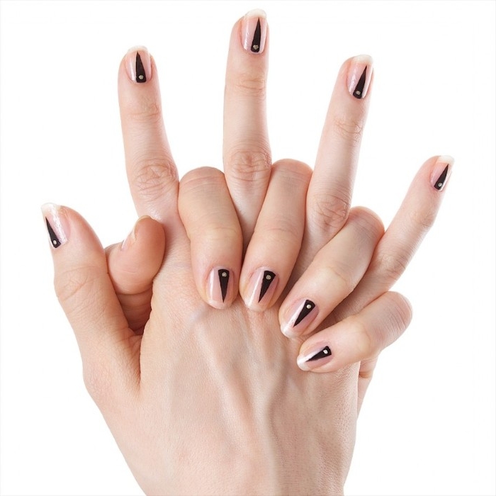 narrow triangles in black, each with a small white dot, painted on the short nude nails, of two hands