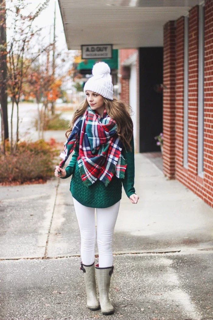 rubber rain boots, over white skinny trousers, and a green, cable knit jumper, worn by a brunette woman, in a white knitted beanie hat, her neck and shoulders covered by blanket shawl
