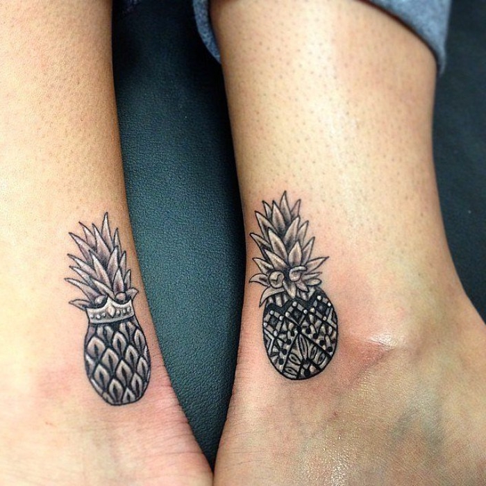 matching friend tattoos, two black and grey pineapples, one wearing a crown, done near the ankle, of two feet