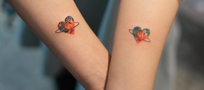 multicolored hearts with thin, black hoops around them, on the lower parts of two linked arms, matching tattoos 