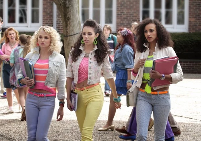 female students dressed in 80s clothes, skinny trousers in blue and yellow, striped and patterned tops in popping colors, retro hairstyles and jewelry