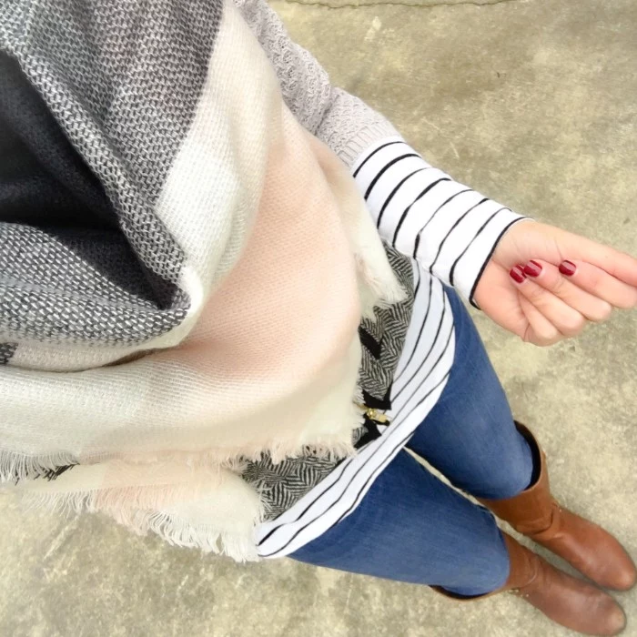 high angle view, of a woman in skinny jeans, and brown leather boots, wearing a striped jumper, and a soft grey, white and pale pink shawl, how to tie a blanket scarf, fast and easy