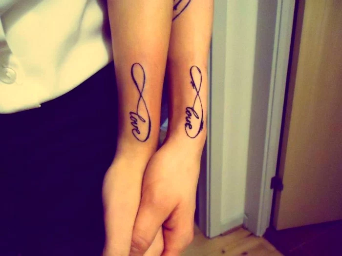 the symbol for infinity, and the word love, tattooed in black ink near the wrists, of two linked arms