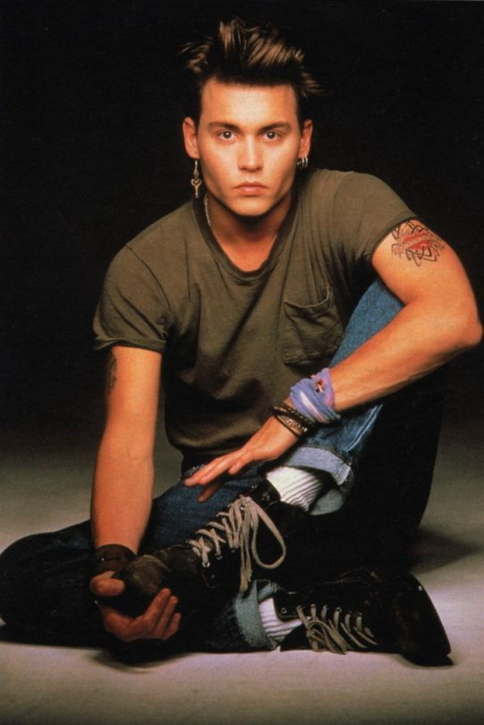 1980s photo of johnny depp, sitting down and wearing a khaki t-shirt, retro jeans and distressed lace up shoes, with white tennis socks, 80s costumes men, quiff hairstyle and an earring