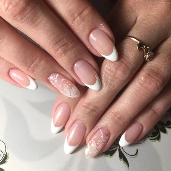 floral motifs in white, painted on the ring finger nails, of two hands with stiletto nails, and classic french manicure