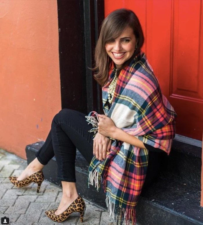 sitting slim brunette woman, dressed in black ankle jeans, with an oversized tartan scarf, wrapped around her shoulders, animal print stilettos and a pearl necklace