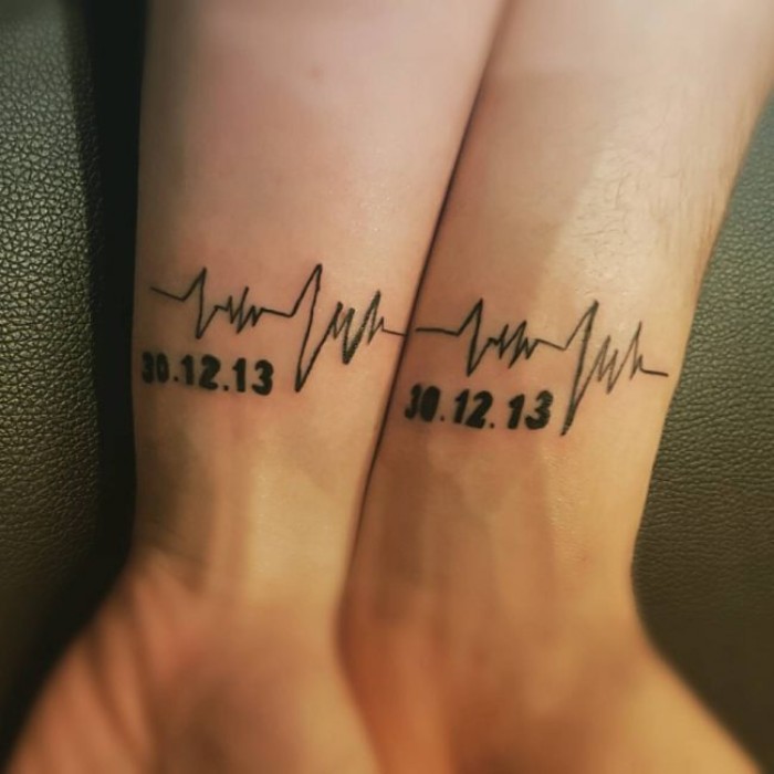 husband and wife tattoos, life line and a date, tattooed in black, on the wrists of two hands, placed next to each other