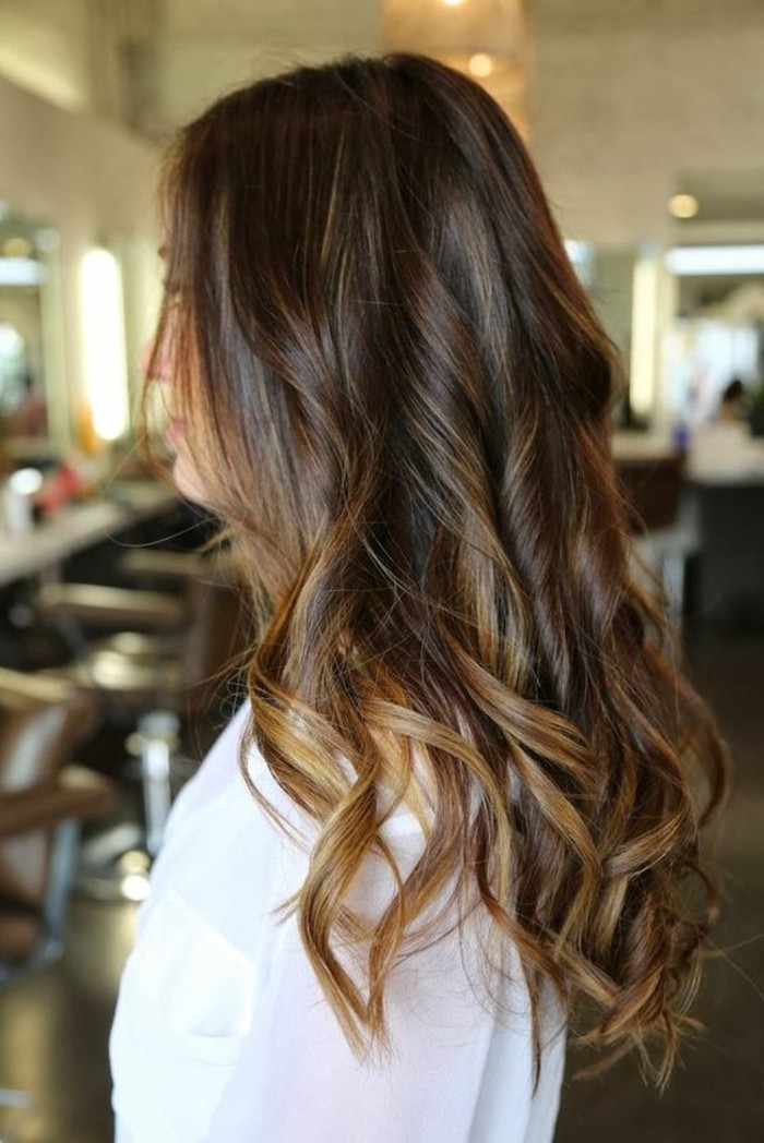 loose curls on long brunette hair, worn by a woman dressed in white, balayage dark hair, with honey blonde highlights