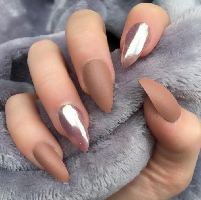 claw-like manicure, on a hand holding a fluffy, pale grey fabric, three dark nude gel nails, and two pink metallic nails