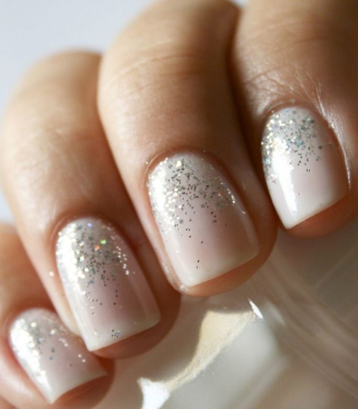 extreme close up of four, short square nails, covered in milky pink, best nude nail polish, decorated with silver glitter