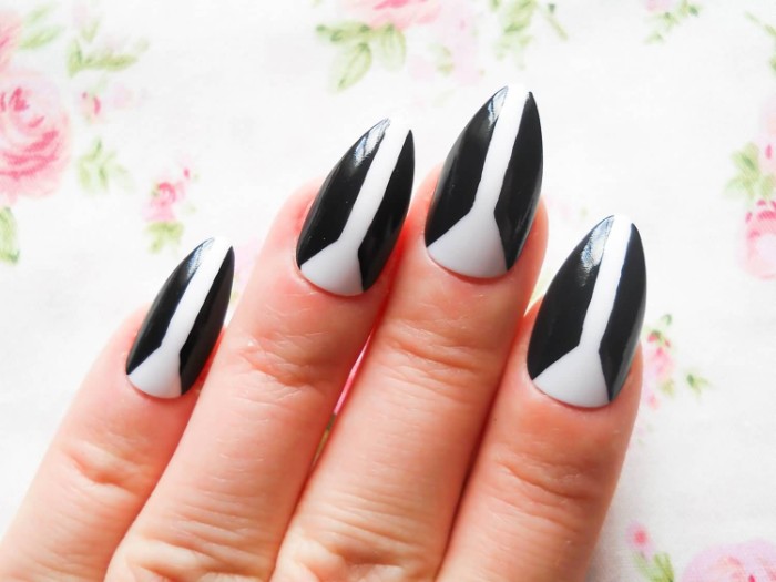 dual color manicure, in black and white, on almond shaped nails, seen in close up, on a floral background