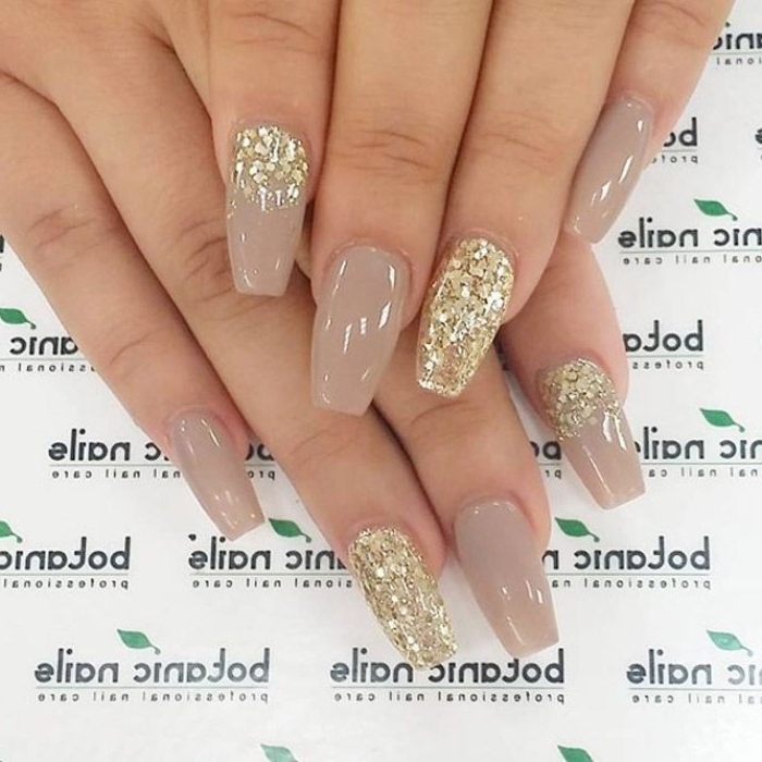 beige nude nail polish color, on a coffin shaped manicure, decorated with gold glitter flakes